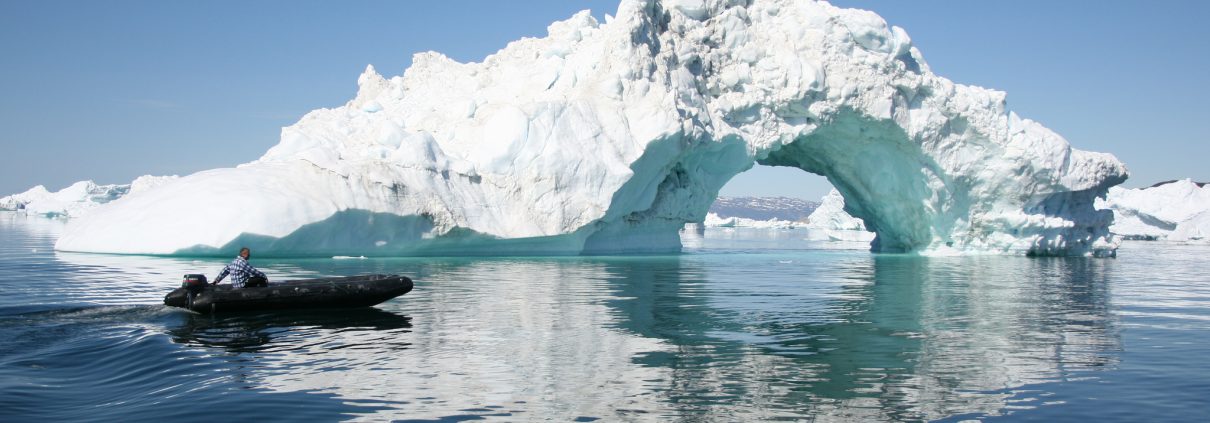 Man in zodiac near iceberg in Greenland, by Leif Taurer